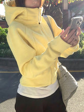 Person wearing a yellow jacket holding a phone outdoors.